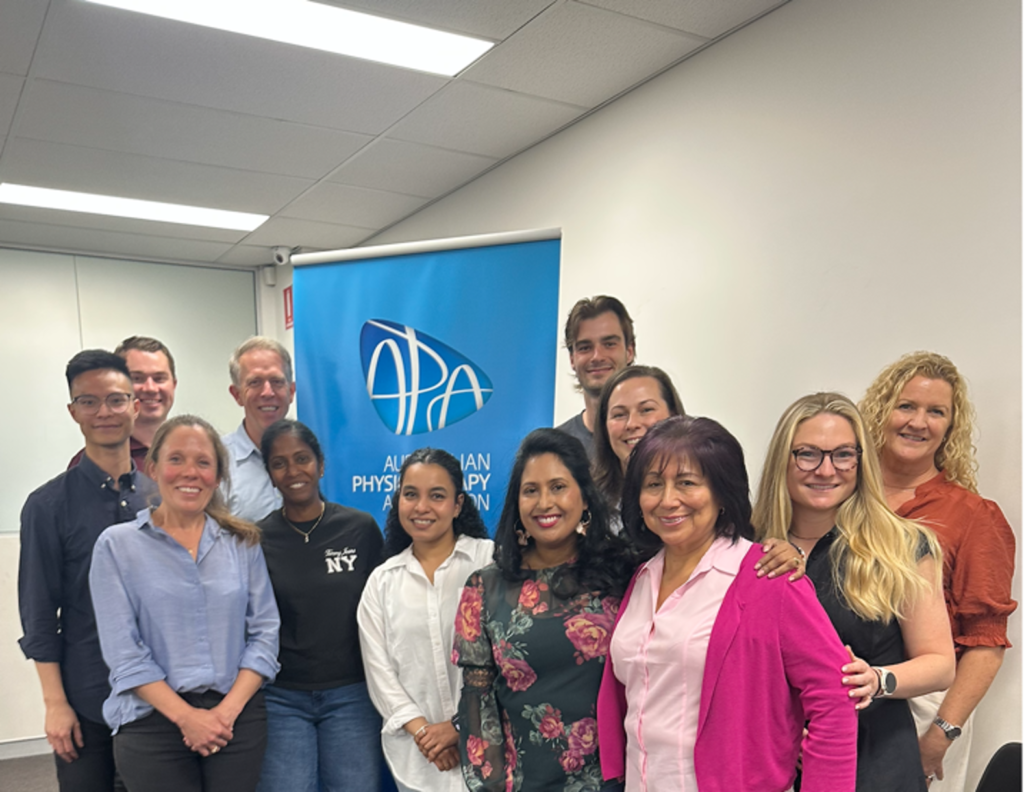 Physiotherapists and attendees standing together in front of an Australian Physiotherapy Association banner at the NSW Clinical Practice Day: Gerontology in North Ryde, Sydney.